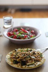 Food served on a table. Ricotta cheese with roasted vegetables and nuts. Tomato, basil and purple onion salad. Selective focus.