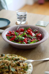 Food served on a table. Ricotta cheese with roasted vegetables and nuts. Tomato, basil and purple onion salad. Selective focus.