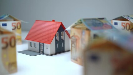 Small plastic house mockup surrounded with euro banknotes in shape of houses, saving money for buying real estate. Great investment in buying property, mortgage concept - Powered by Adobe
