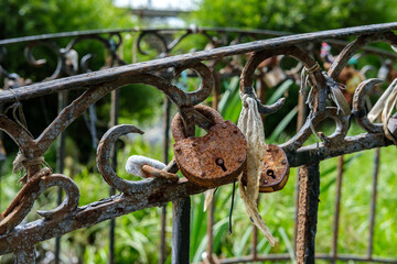 Several old rusty locks hang from the metal railings of the bridge as a sign of the wedding tradition.