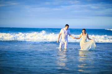 Fototapeta na wymiar couple in wet clothing goes in water at beach.