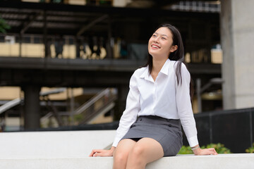 Young beautiful Asian businesswoman in the city outdoors