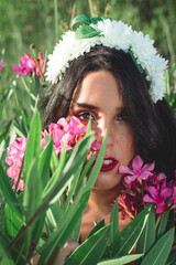 Pretty and brunette girl dressed as a bride in a garden next to some flowers