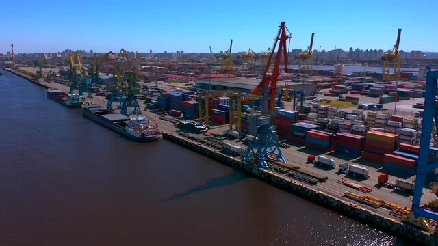 Aerial view of a row of construction or cargo cranes on the river bank. Ship docks off Kanonersky Island. Industrial port with water barges and transport tugs.