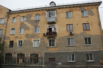 Fototapeta na wymiar Bright balcony in flowers on a shabby wall of an old building