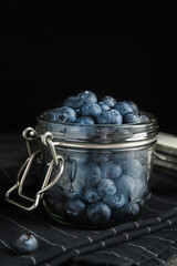 Tasty ripe blueberries in glass jar on table