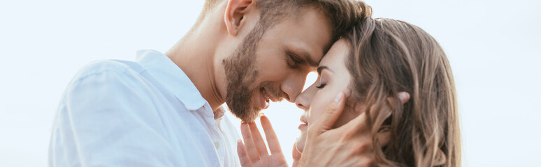 panoramic crop of handsome and bearded man touching face of beautiful girlfriend outside