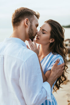 beautiful woman with closed eyes kissing with bearded man