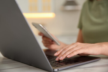 Woman working with modern laptop at marble table, closeup