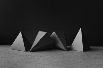 Platonic solids figures geometry. Abstract geometrical figures still life composition. Three-dimensional prism pyramid objects on black gray background.