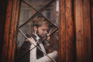 Young stylish newlyweds are hugging behind old rustic wooden door. wedding day.