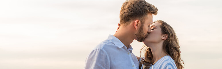 panoramic shot of bearded man kissing girlfriend outside