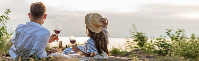 horizontal concept of couple holding glasses with red wine outside
