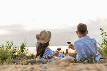 Back view of couple holding glasses with red wine outside