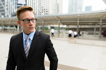 Young handsome blond businessman thinking in the city outdoors