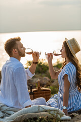 side view of couple holding glasses while drinking red wine near lake