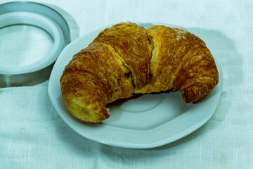 still life con taza de cafe con medialuna y jarra con leche sobre mantel blanco