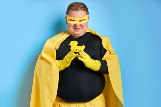 portrait of tricky caucasian superhero man isolated over blue background. fat man is thinking, he conceived something insidious