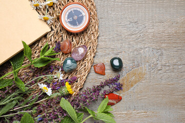 Flat lay composition with different gemstones and healing herbs on wooden table, space for text