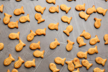 Delicious goldfish crackers on grey table, flat lay
