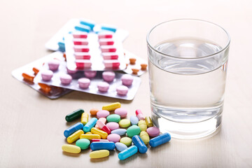 Colorful pills with glass of water on wooden table