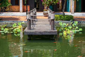 Fototapeta na wymiar Wooden pier on pond in a tropical garden in Danang, Vietnam. Travel and nature concept