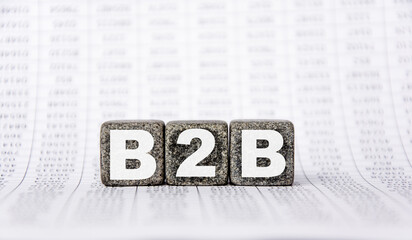 B2B , business to business marketing, on stone granite cubes on background from financial reports. Strong business concept