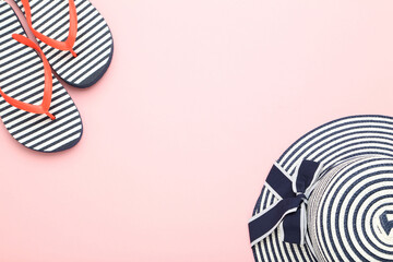 Summer straw hat with flip flops on pink background