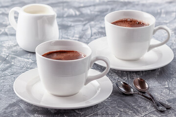 Freshly brewed aromatic coffee with cream on a gray background