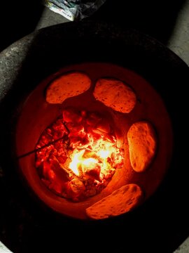 Roti and Naans getting cooked in an Indian oven  called Tandoor