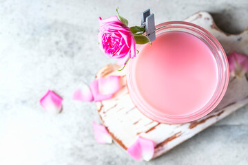 Ayurvedic rose moon milk. A trendy relaxing form of drink before bed. Milk with rose petals on a light concrete background. View from above