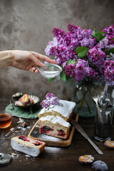 Table setting with flowers. Powdered sugar plum cake. Homemade baking.