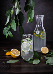 Classic lemonade with mint and ice in a glass on a dark table. Bottle with a refreshing drink. 