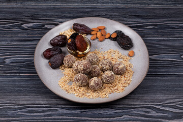 Energy balls with dates, sweets proper nutrition homemade on dark background. Made from apricots, almonds, pine nuts and prunes, with honey.  Dark wooden table, close-up, copy space