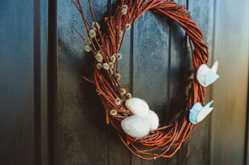 Wicker wreath of willow branches, decorated with birds and eggs. The design of the entrance door is hand made