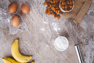 Healthy baking ingredients - flour, almond nuts,  eggs, over a stone table background. Bakery background frame. Top view, copy space.