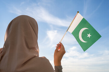 Silhouette of muslim woman in head scarf with Pakistan flag at blue sunset sky. Concept of freedom - obrazy, fototapety, plakaty