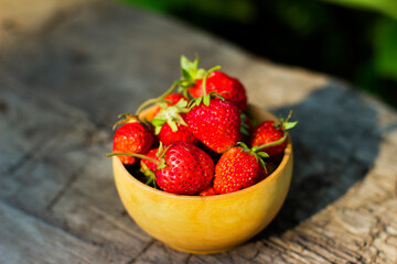 
Red ripe strawberries in a bowl on a wooden background. Fresh strawberries from the garden. Summer healthy food concept. Healthy organic sweet fruits.