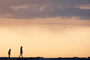 two little kid walking forward on sunset. silhouette