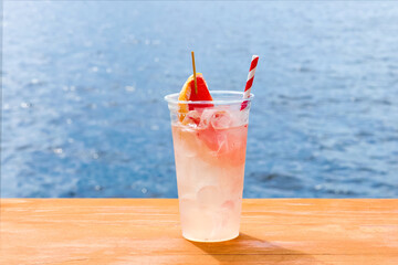 Cocktail with grapefruit on the background of the sea, a refreshing drink with ice