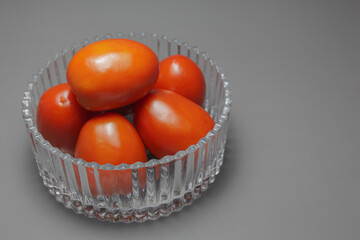 Fresh Tomato In Glass bowl On Gray Background.