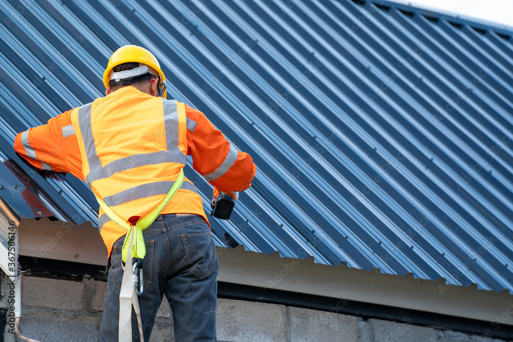 Poster roofer working on roof structure of building on construction site.