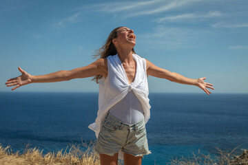 Authentic shot of an young carefree woman tourist is feeling free and breathing deeply with wide...