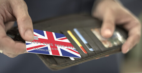Man pulls credit card with flag of the United Kingdom out of his wallet, fictional card number