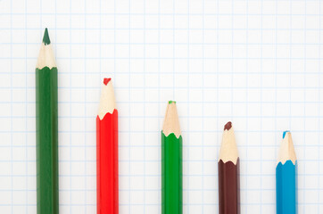sharp  green  pencil and colored blunt pencils on a writing-book leaf.