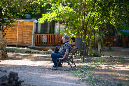 Man At Park On Bench With Plastic Visor Due To Covid