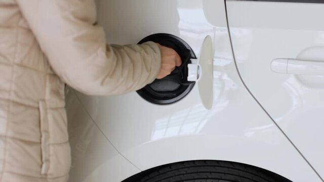 Closeup woman coming to the EV and unplugging a charger connector into the electric car. Zero emission vehicle
