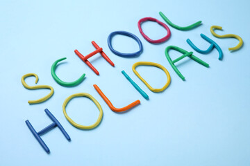 Phrase School Holidays made of modeling clay on light blue background