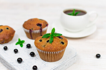 Cupcakes with black currant and mint leaves on a white plate. Selective focus.