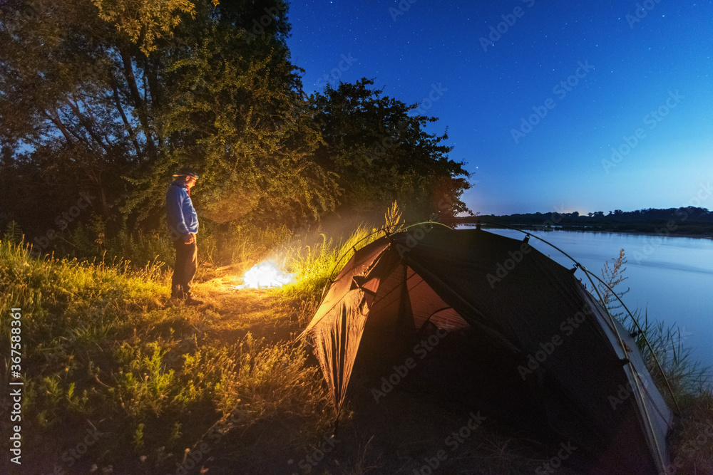 Wall mural comet neowise in the night sky over the river, with the milky way and a tourist with a tent